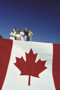 Un groupe de personnes au-dessus d’un immense drapeau Canadien.