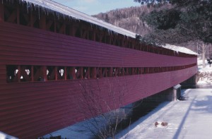 Un pont couvert rouge s'étend au-dessus d'une voie d'eau gelée.